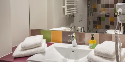 Wanderurlaub - Umgebungsschwerpunkt: Fluss - Fließ - Das farbenfrohe Badezimmer mit geräumiger Dusche - Explorer Hotel Ötztal
