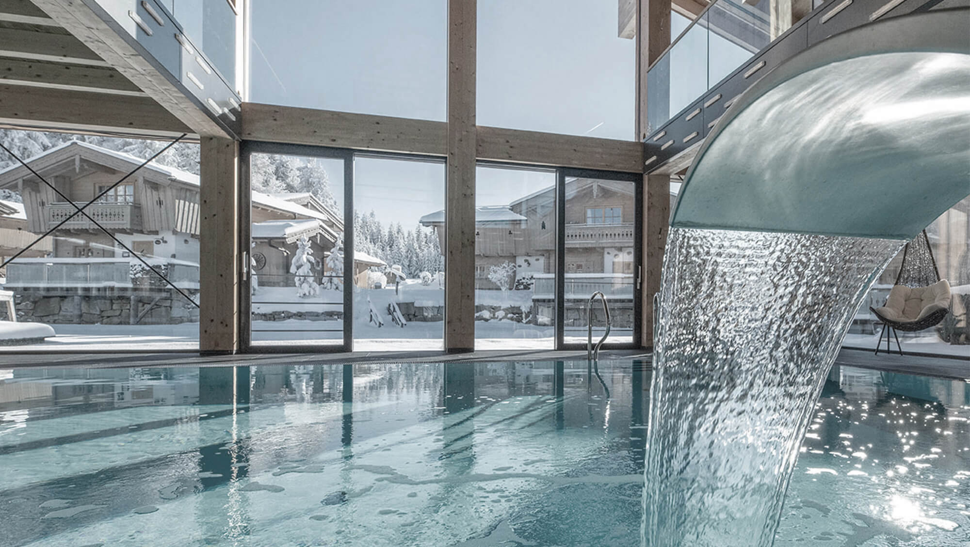 Wanderhotel: INNs HOLZ Ausblick vom Indoorpool auf das Chaletdorf im Winter - INNs HOLZ Chaletdorf