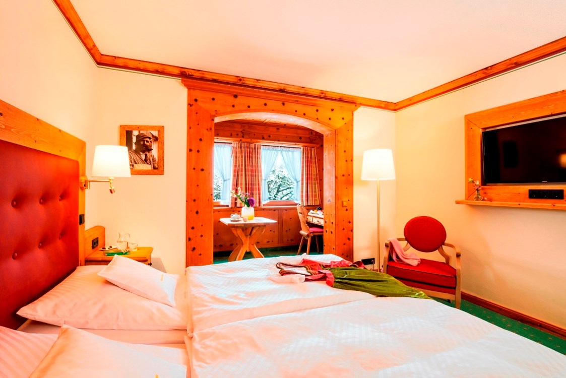 Wanderhotel: Das Doppelzimmer Dorfblick, in Zirbenholz ausgestattet hat ein kleines Stüberl mit 2-Sitzer und Schreibtisch. - Parkhotel Wallgau